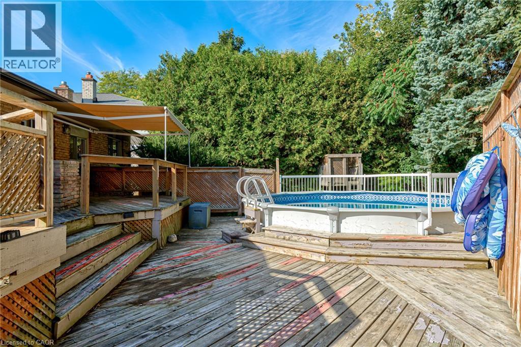 Multi-level wooden deck with an above-ground pool, a retractable awning, and a privacy fence - 8 Bonnylyn Drive, Kitchener, ON