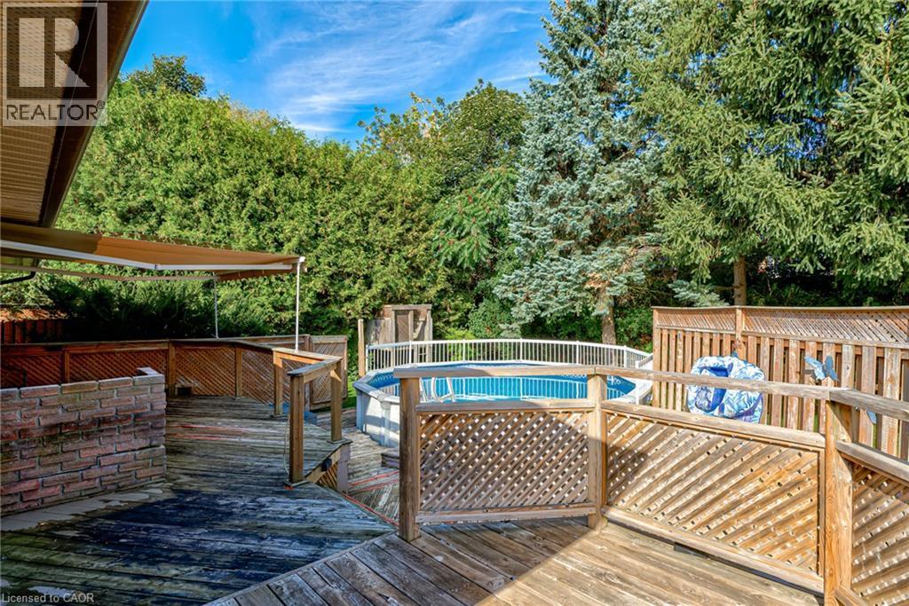 Expansive wooden deck with lattice railing, a partial brick wall, and an awning - 8 Bonnylyn Drive, Kitchener, ON