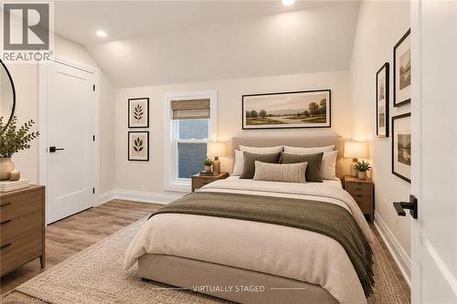 Vaulted ceiling with recessed lighting, wood-finish flooring, white paneled door with black hardware, and window with natural fiber shade - 73 Clinton Street, Hamilton, ON 