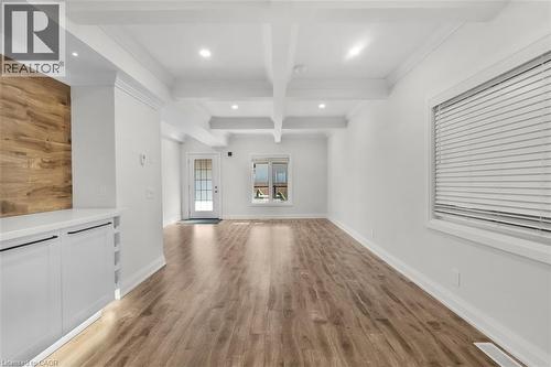 Wood-finish flooring throughout, bright white walls, recessed ceiling lights, and exposed ceiling beams - 73 Clinton Street, Hamilton, ON 