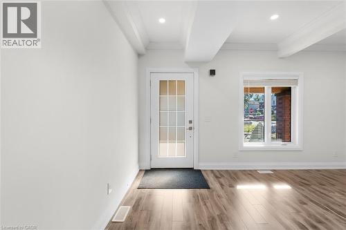 Wood-finish flooring with a white trim, white walls, and a glass-paneled door - 73 Clinton Street, Hamilton, ON 