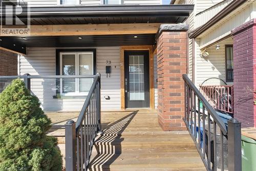 Covered entry porch featuring wood-finish decking and dark metal railings - 73 Clinton Street, Hamilton, ON 