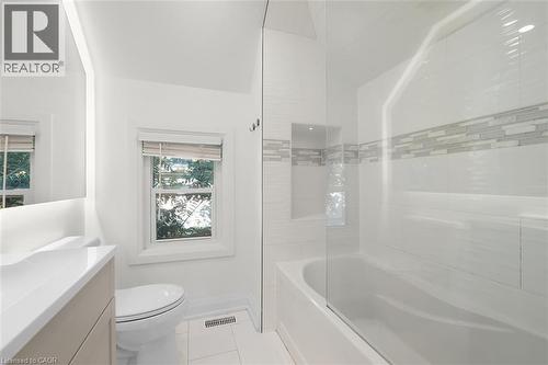 Glass-enclosed bathtub and shower combination with a decorative tile inlay - 73 Clinton Street, Hamilton, ON 