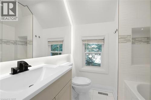 White vanity with integrated sink, matte black faucet, and a large illuminated mirror - 73 Clinton Street, Hamilton, ON 