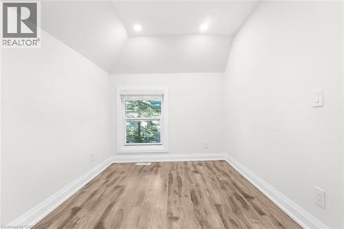 Room featuring wood-finish flooring, white trim, a single window with blinds, recessed lighting, and sloped ceiling details - 73 Clinton Street, Hamilton, ON 
