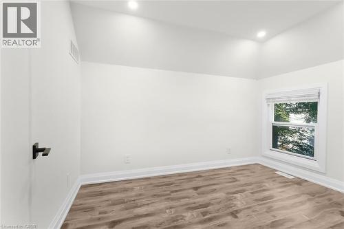 Vaulted ceilings with recessed lighting, wood-finish flooring, white trim, and a window with blinds - 73 Clinton Street, Hamilton, ON 