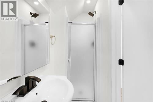 White wall-mounted sink with a dark bronze faucet, accompanied by a rectangular mirror - 73 Clinton Street, Hamilton, ON 