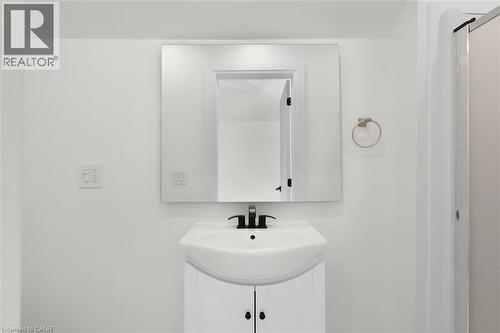 Modern vanity with integrated sink, black-finish faucet, and a large rectangular mirror - 73 Clinton Street, Hamilton, ON 