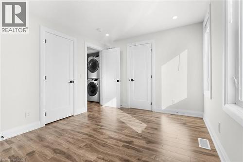 Wood-finish flooring, white walls, multiple windows, recessed lighting, and a stacked washer and dryer unit - 73 Clinton Street, Hamilton, ON 