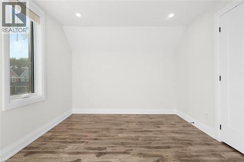 White walls, wood-finish flooring, recessed lighting, and a white interior door - 73 Clinton Street, Hamilton, ON 