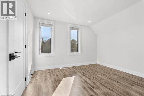 Recessed lighting, wood-finish flooring, two windows, white trim, and a white door with matte black hardware - 73 Clinton Street, Hamilton, ON 