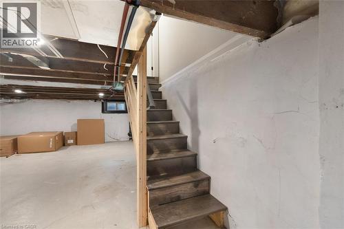 Staircase with wood-finish treads and an unfinished wood handrail, concrete flooring, and exposed ceiling joists - 73 Clinton Street, Hamilton, ON 