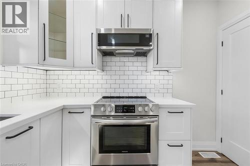 White shaker-style cabinetry, stainless steel appliances, subway tile backsplash, and light-toned countertops - 73 Clinton Street, Hamilton, ON 