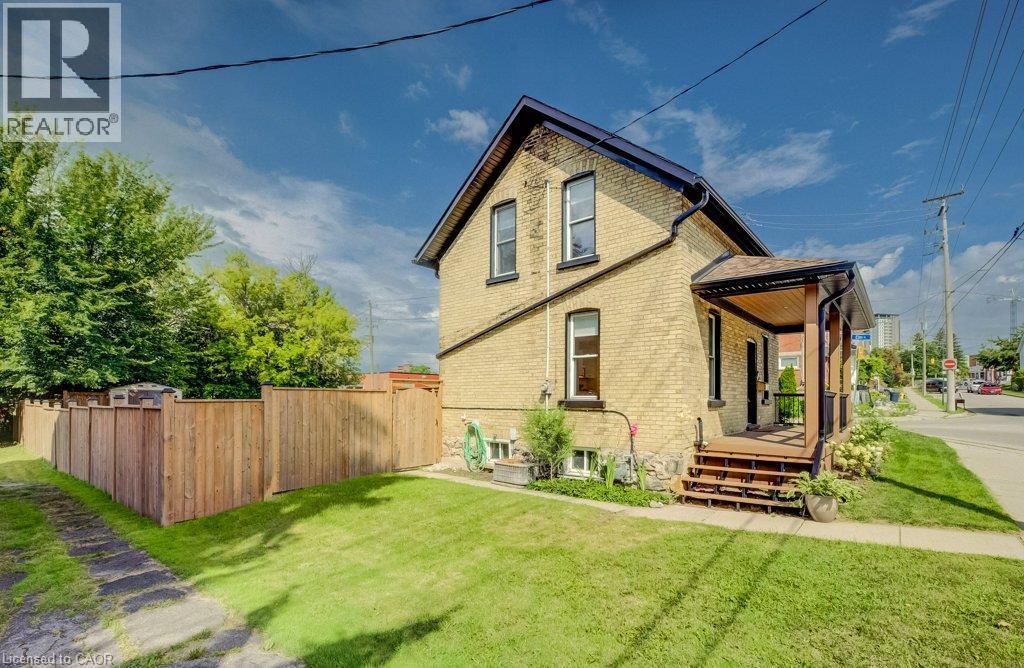 Brick exterior with a covered porch featuring wood decking - 185 Strange Street, Kitchener, ON - Outdoor