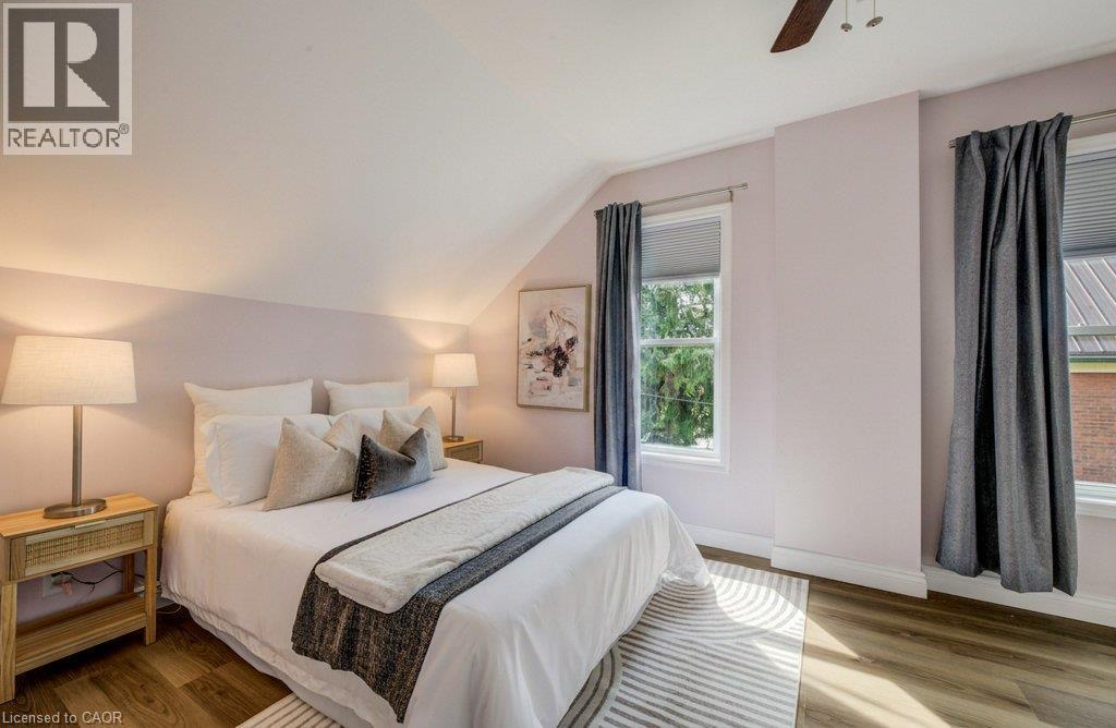 Sloped ceiling with recessed lighting, wood-finish flooring, two windows with window treatments, and a ceiling fan - 185 Strange Street, Kitchener, ON - Indoor Photo Showing Bedroom