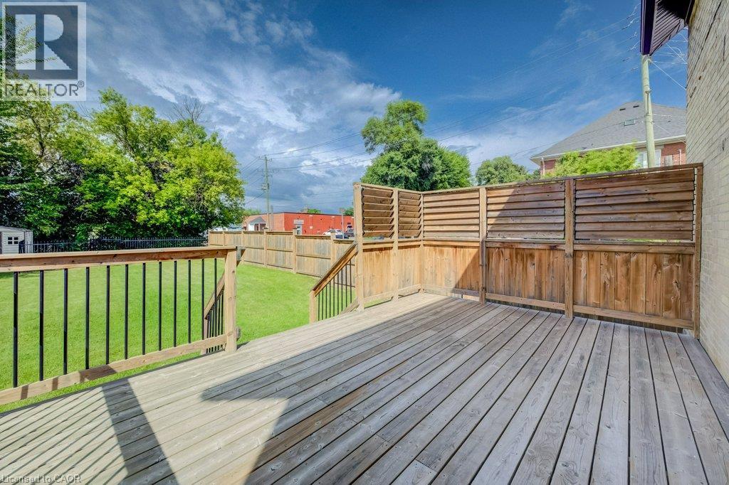 Expansive wooden deck with slatted privacy fencing, leading to a grassed yard with perimeter wood fencing - 185 Strange Street, Kitchener, ON - Outdoor With Deck Patio Veranda
