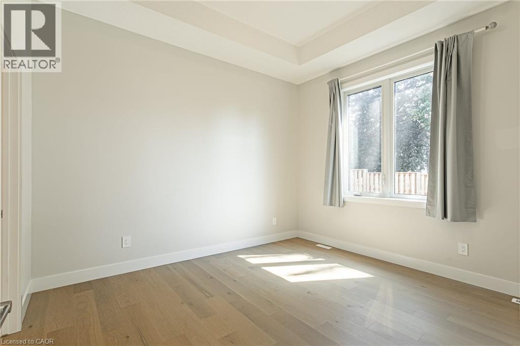 Tray ceiling detail, wood-finish flooring, white trim, and a large window - 7966 Fallon Drive Unit# 18, Lucan Biddulph (Twp), ON - Indoor Photo Showing Other Room
