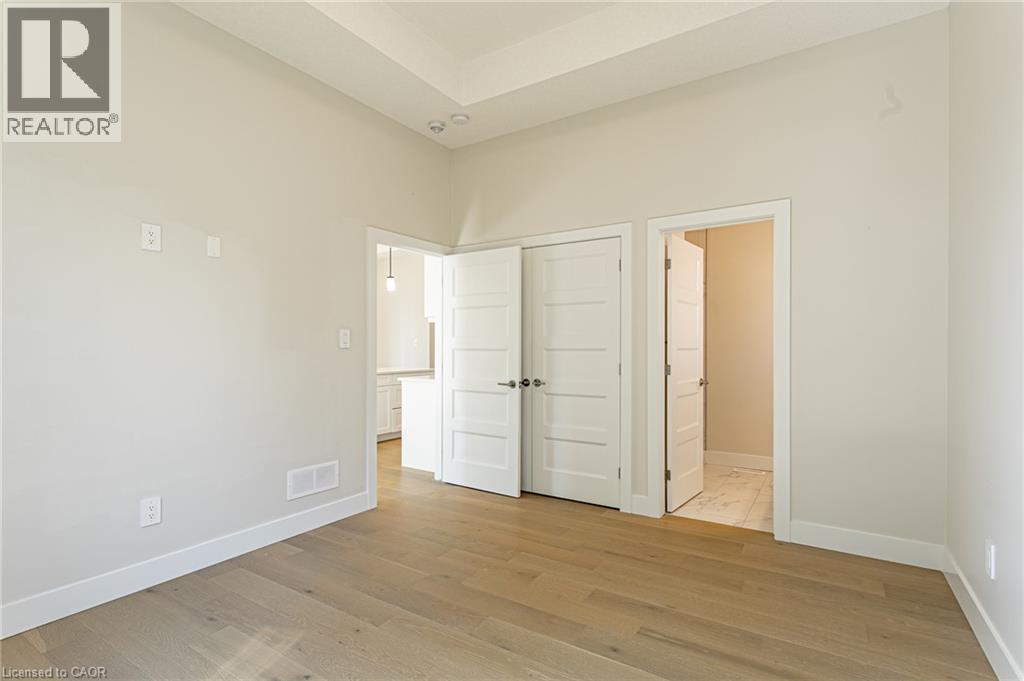 Wood-finish flooring, white trim, recessed lighting, and a tray ceiling - 7966 Fallon Drive Unit# 18, Lucan Biddulph (Twp), ON - Indoor Photo Showing Other Room