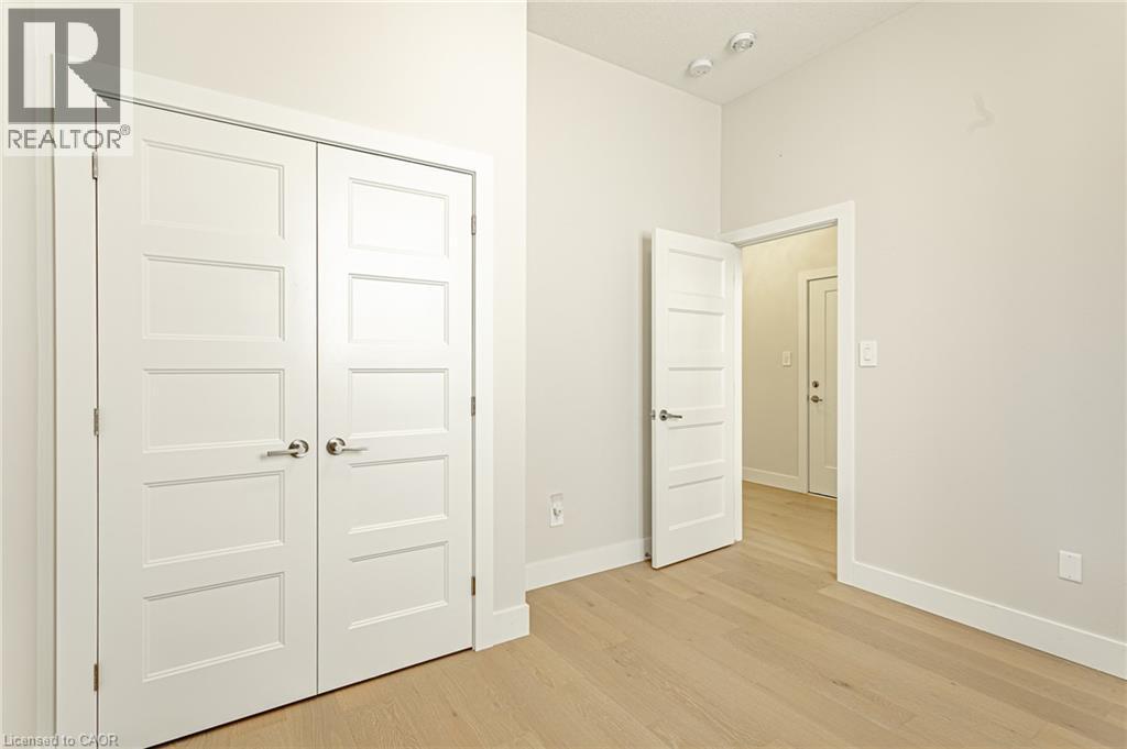 Light wood-finish flooring with white baseboards, a four-panel interior door, and a two-door closet - 7966 Fallon Drive Unit# 18, Lucan Biddulph (Twp), ON - Indoor Photo Showing Other Room