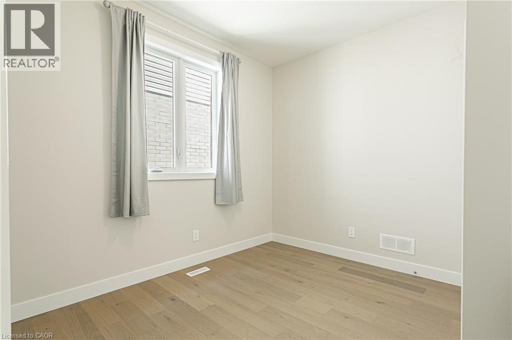 Neutral wall color, wood-finish flooring, white window trim, and white baseboards - 7966 Fallon Drive Unit# 18, Lucan Biddulph (Twp), ON - Indoor Photo Showing Other Room