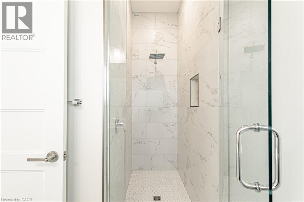 Walk-in shower with full-height tile surround, rain shower head, built-in niche, and glass enclosure with chrome hardware - 7966 Fallon Drive Unit# 18, Lucan Biddulph (Twp), ON - Indoor Photo Showing Bathroom