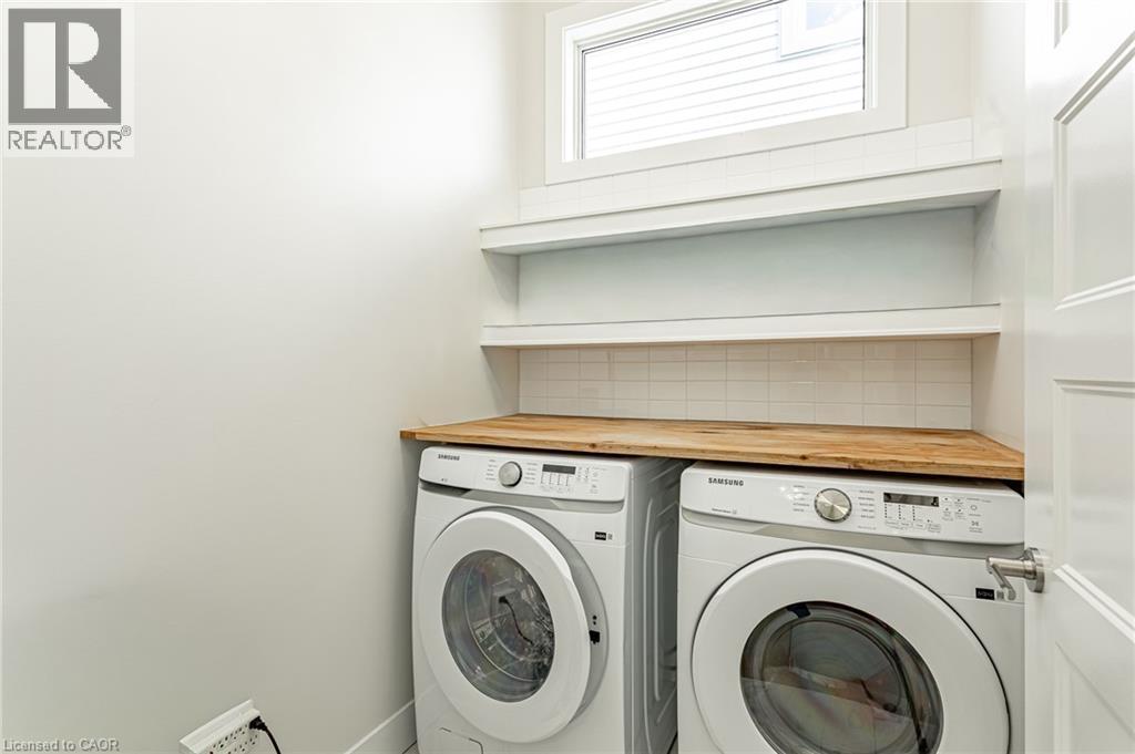 Wood-finish countertop, white subway tile backsplash, and built-in shelving - 7966 Fallon Drive Unit# 18, Lucan Biddulph (Twp), ON - Indoor Photo Showing Laundry Room
