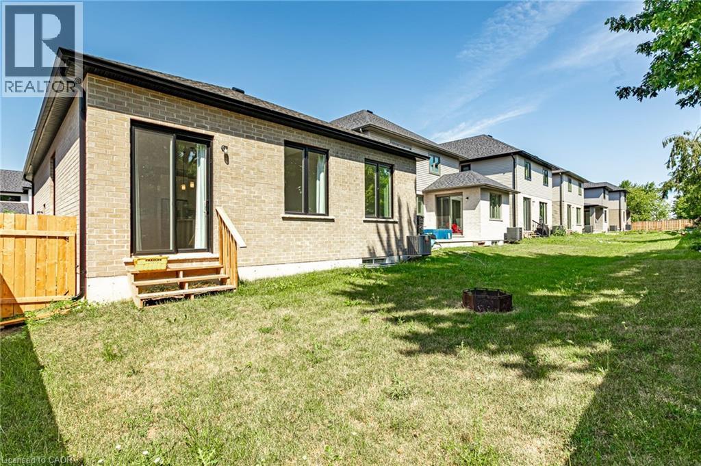 Expansive backyard featuring a grass lawn, a wood fence, and a brick exterior with sliding glass doors - 7966 Fallon Drive Unit# 18, Lucan Biddulph (Twp), ON - Outdoor