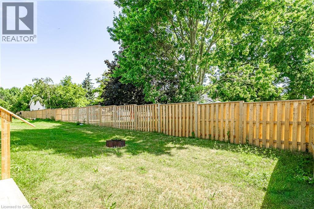 Expansive yard featuring a wooden privacy fence, green lawn, and mature trees - 7966 Fallon Drive Unit# 18, Lucan Biddulph (Twp), ON - Outdoor