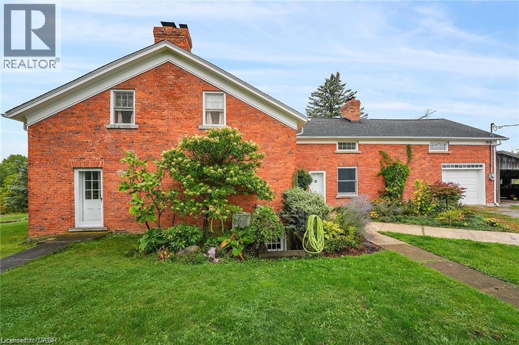 Brick exterior with white trim, established landscaping, attached garage with a white door, and an asphalt shingle roof - 2432 Seburn Road, Fonthill, ON - Outdoor With Exterior