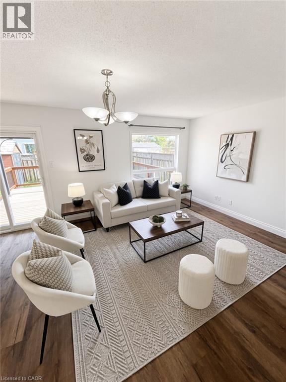 Wood-finish flooring, white walls, and a contemporary chandelier - 765 Angler Way, Waterloo, ON - Indoor Photo Showing Living Room