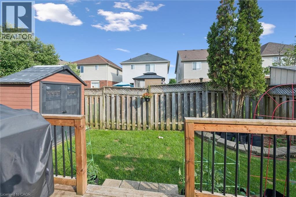 Expansive backyard featuring a manicured lawn, wood fencing, and a storage shed - 765 Angler Way, Waterloo, ON - Outdoor With Deck Patio Veranda