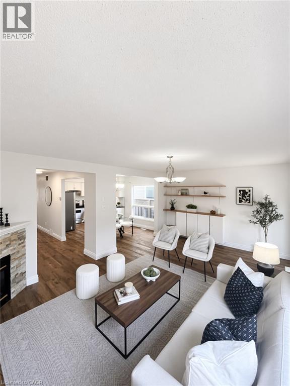 Wood-finish flooring throughout, modern fireplace with stacked stone surround, built-in shelving, and recessed lighting - 765 Angler Way, Waterloo, ON - Indoor Photo Showing Living Room With Fireplace