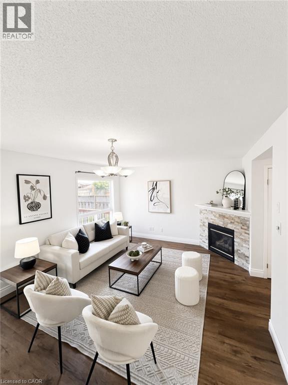 Wood-finish flooring, white walls, stone-faced fireplace with hearth, and a ceiling fan with integrated lighting - 765 Angler Way, Waterloo, ON - Indoor Photo Showing Living Room With Fireplace