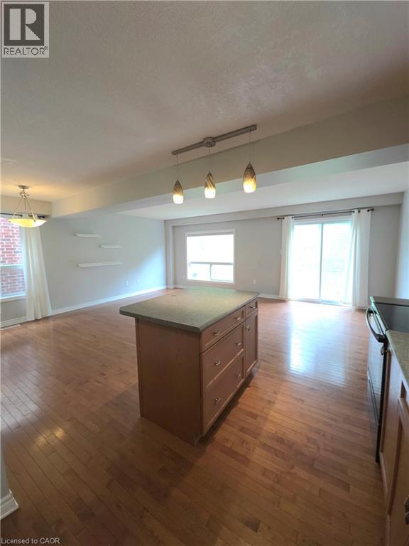 Hardwood flooring throughout, kitchen island with built-in storage, sliding glass door, white framed windows, and pendant lighting - 998 Mapleridge Street, London, ON - Indoor Photo Showing Other Room