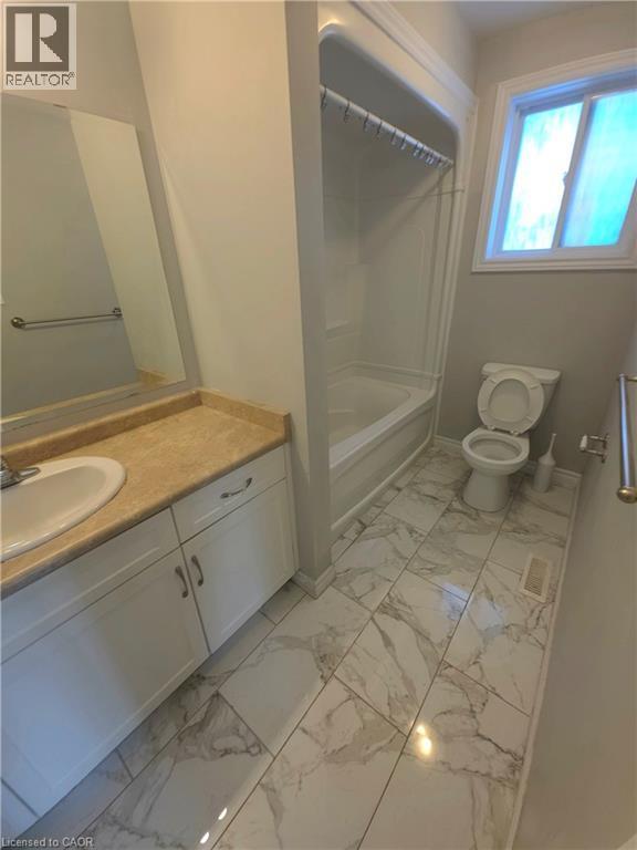 White vanity with built-in sink, tan countertop, and extensive wall mirror - 998 Mapleridge Street, London, ON - Indoor Photo Showing Bathroom