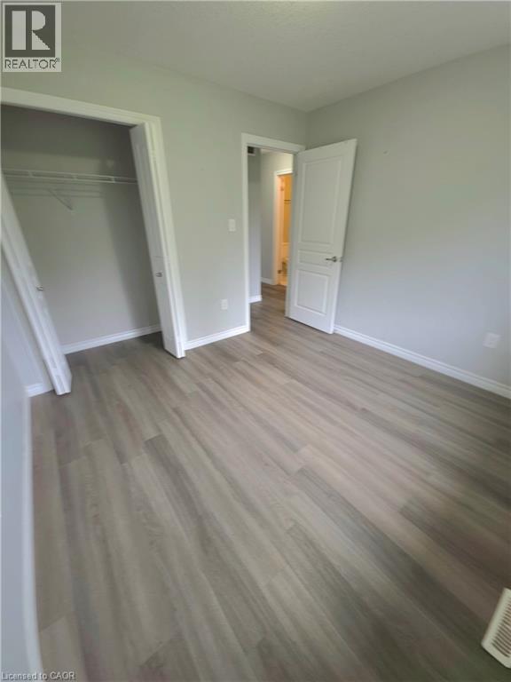 Wood-finish flooring throughout, light gray wall paint, white trim, and a bi-fold closet door - 998 Mapleridge Street, London, ON - Indoor Photo Showing Other Room