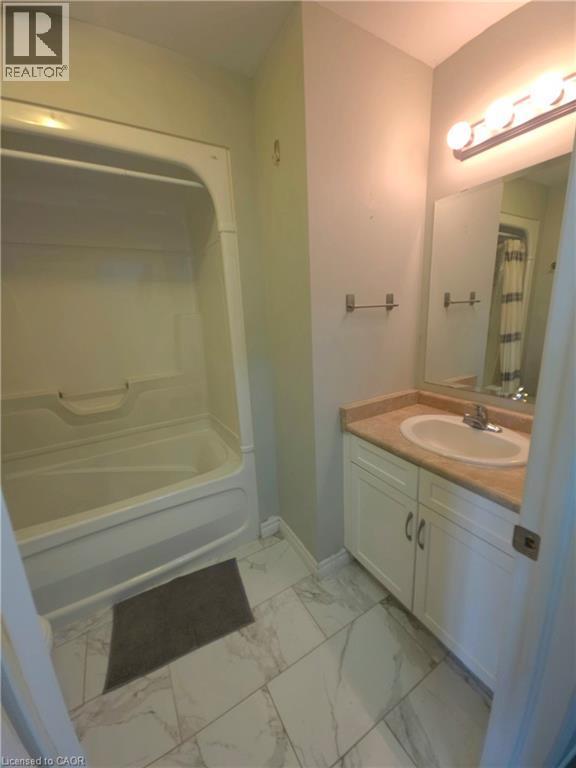 Bathroom featuring a white tub/shower combination, white vanity with cabinet storage, light-toned countertop, and tile flooring - 998 Mapleridge Street, London, ON - Indoor Photo Showing Bathroom