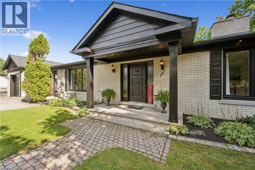 Light-colored brick exterior with black trim, a covered entryway with substantial columns, a paver walkway, an attached garage, and mature landscaping - 267 Abraham Street, Cambridge, ON - Outdoor