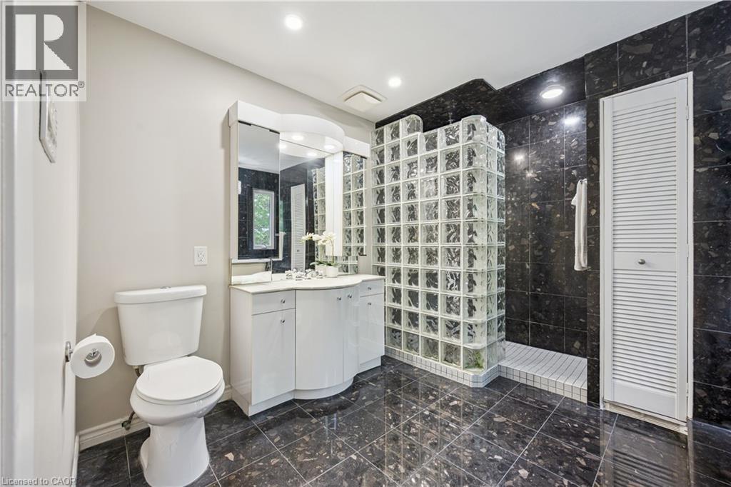 Tiled flooring, white vanity with integrated sink, glass block shower enclosure, dark tiled shower surround, recessed lighting - 267 Abraham Street, Cambridge, ON - Indoor Photo Showing Bathroom