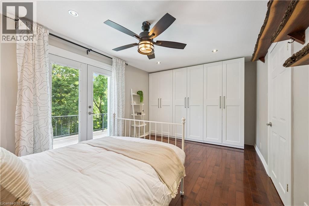 Hardwood flooring, recessed lighting, ceiling fan with light fixture, built-in white panel cabinetry, and French doors leading to a balcony - 267 Abraham Street, Cambridge, ON - Indoor Photo Showing Bedroom