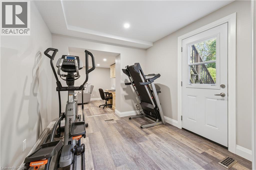 Wood-finish flooring throughout, recessed lighting, and a white paneled door with a glass insert - 267 Abraham Street, Cambridge, ON - Indoor Photo Showing Gym Room