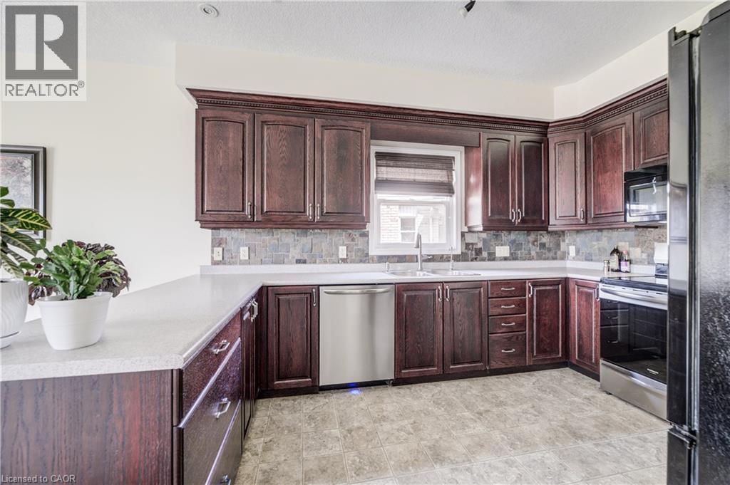 Kitchen featuring wood-finish cabinetry, light-toned countertops, and a tiled backsplash - 64 Kropf Drive, Baden, ON - Indoor Photo Showing Kitchen