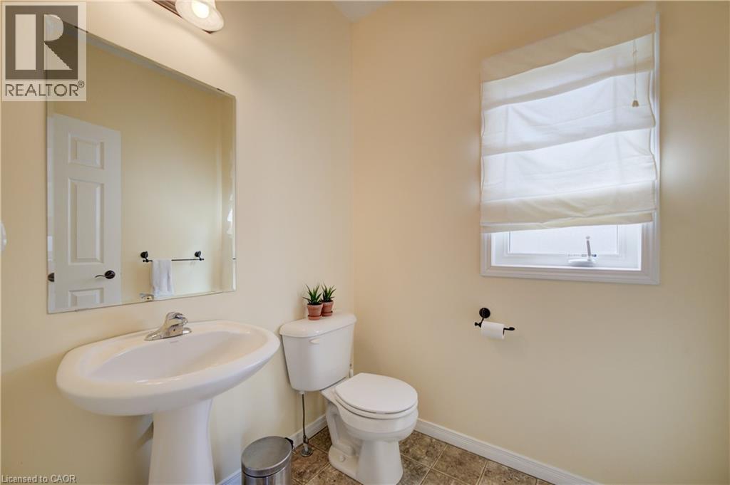 Pedestal sink with chrome faucet, wall-mounted mirror, toilet, window with roman shade, and Linoleum flooring - 64 Kropf Drive, Baden, ON - Indoor Photo Showing Bathroom