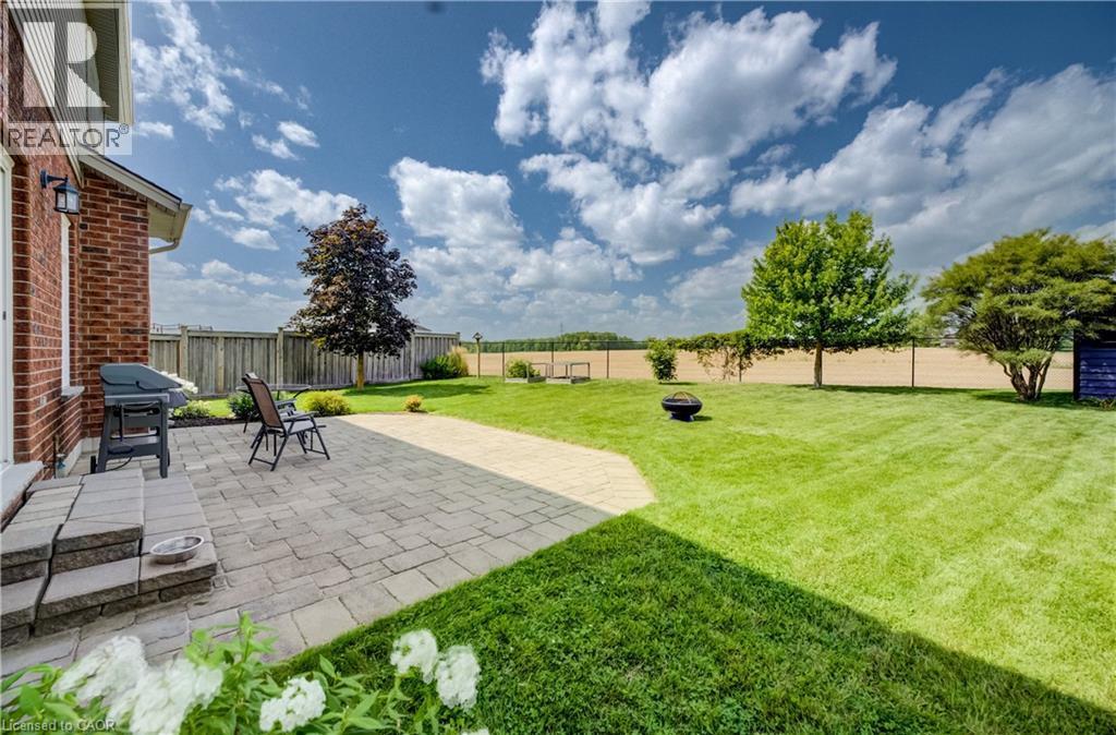 Expansive backyard featuring a paver patio with steps, a manicured lawn, and mature trees - 64 Kropf Drive, Baden, ON - Outdoor