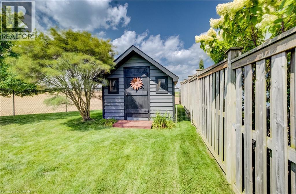 Grassed yard featuring a wood storage shed with shiplap siding, wood privacy fencing, and mature trees - 64 Kropf Drive, Baden, ON - Outdoor