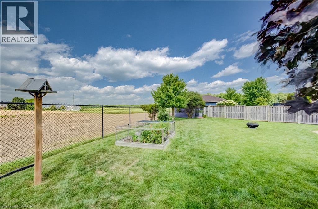 Expansive backyard featuring a manicured lawn, raised garden beds, and a wood privacy fence - 64 Kropf Drive, Baden, ON - Outdoor