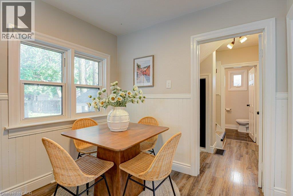 Warm wood-finish flooring, white wainscoting, and large windows - 99 Shantz Lane, Kitchener, ON - Indoor Photo Showing Dining Room