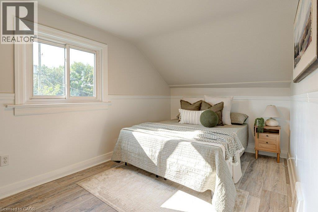 Angled ceiling with a rectangular window, wood-finish flooring, and white wall paneling - 99 Shantz Lane, Kitchener, ON - Indoor Photo Showing Bedroom