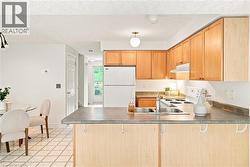 Kitchen featuring wood-finish cabinetry, stainless steel sink, and light-colored countertops - 