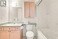Bathroom featuring a built-in vanity with wood-finish cabinetry, integrated sink, and an overhead wall-mounted light fixture - 
